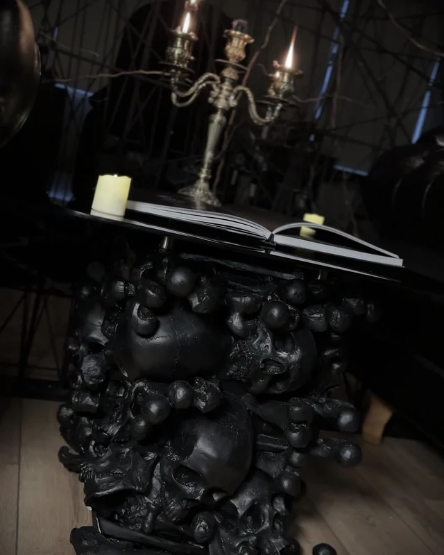 Mesa de caveiras com candelabro e livro aberto